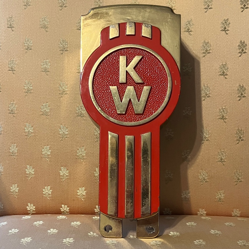 Metal Kenworth gold 50th anniversary truck hood pull emblem.